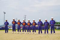 消防団員がヘルメットと青い制服を着て横一列に整列している大会の様子の写真