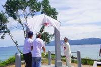 3名の方が幸せの鐘に掛けられた白い布の先にある紅白の紐を引っ張ろうとしている写真