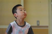 男の子が頬をふくらませて前を見ながらスイカの種を飛ばしている瞬間の写真