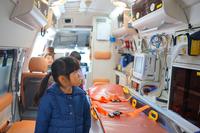 救急車の中でストレッチャーや医療機器を見学している子どもたちの写真