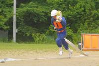 ビブス「1番」を着た団員がホースを持って走り出す、訓練中の動作を捉えた写真