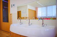 明るい部屋の中に設置された洗面台に、銀色の蛇口が三つ横並びに配置されている写真