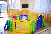 明るい部屋の中に、赤・青・黄・緑などのパネルで囲まれたカラフルなベビーサークルが設置されている写真