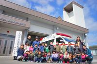 救急車の前で防災学習に参加した園児たちと大人が記念写真を撮っている写真