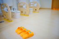 子供用のトイレに象の形をした可愛らしい仕切りが設置されており、手前にはオレンジ色のスリッパが三足きれいに並べられている写真