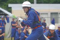 団員が真剣な表情でホースを構え、放水動作に集中している様子の写真