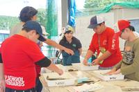 参加している子ども達が白いトレーに入った魚を触ったりしている写真