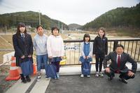 女子高校生1名、小学生4名と市長が「新井田橋」と書かれた橋名板が設置された橋で記念撮影をしている写真