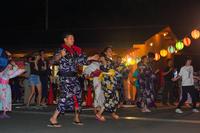 大勢の人たちが提灯の明かりの下で楽しげに盆踊りを踊っている夜の写真