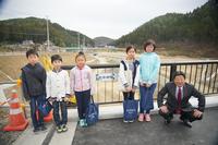 2名の男子小学生、3名の女子小学生と市長が「新井田橋」と書かれた橋名板が設置された橋の上で記念撮影をしている写真