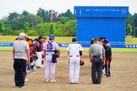 野球の試合終了後、両チームの選手たちが審判とともにグラウンドに並び礼をしている様子の写真