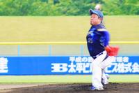 紺色のユニフォームのピッチャーが真剣な表情でボールを投げている写真