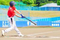 赤いユニフォームの選手が豪快にスイングし、バットがボールに当たる瞬間の様子の写真