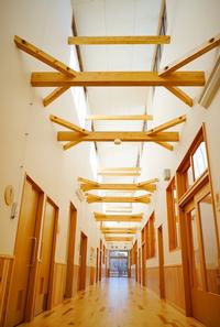 天井の梁が特徴的で、木のぬくもりを感じられる長い廊下の写真