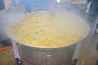 大きな鍋にネギなどが入ったサケ汁が調理されている写真