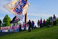 芝生の上に立つ複数の人々が横一列に並び、それぞれが「BEARS」と大きく書かれた旗を掲げている様子を写した写真