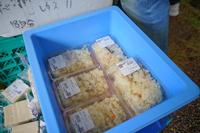 青いコンテナにパック詰めされた炊き込みご飯が並んでおり、値札も付けられている直売コーナーの写真