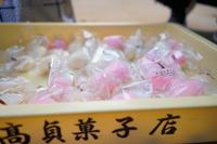透明な袋に個包装された紅白のまんじゅうがたくさん入れられた黄色い箱に「高貞菓子店」と書かれている地元和菓子の販売の写真