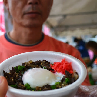 白い容器のどんぶりに温泉卵、甘辛く煮た牛肉、紅しょうが、ねぎがのったご飯を写した写真