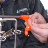 棒の先についたオレンジ色のガラスの元を、男性講師がバーナーで熱しながら、女性が形を整えている様子をアップで撮影した写真