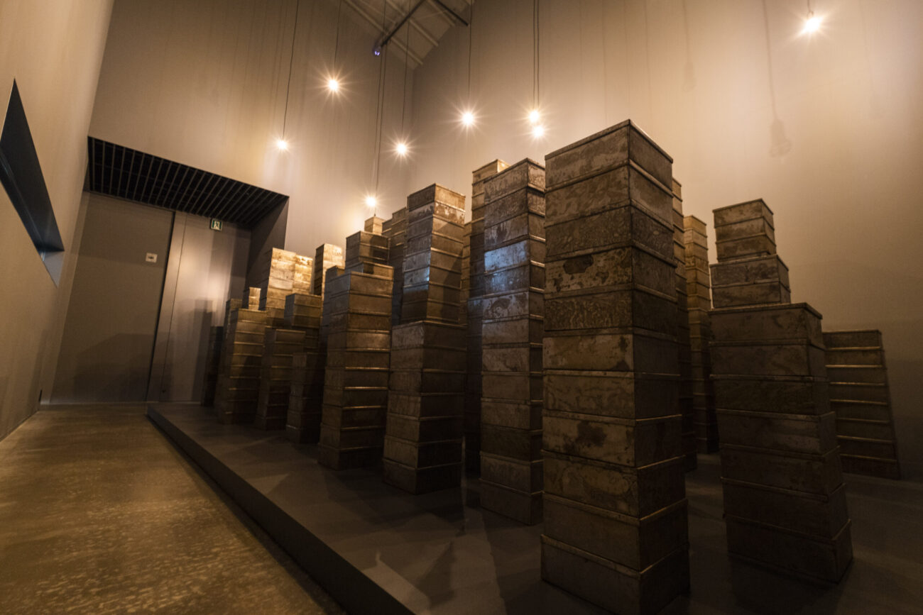 錆びた金属の箱が塔のように積み上げられた空間の写真