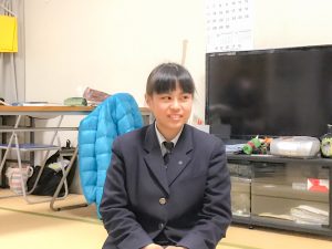 長机とテレビを背にして座り笑顔を見せている佐藤かおりさんの写真