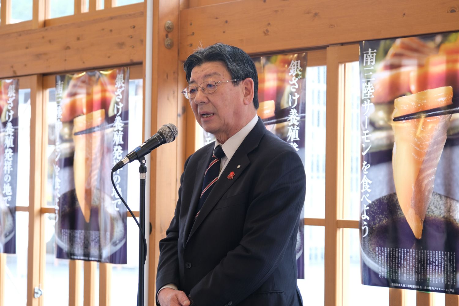 スーツを着た佐藤町長がマイクの前で話している写真