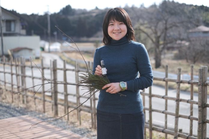 左手には枝付きの植物、右手には小さなスプレーボトルを持っている大渕さんの写真
