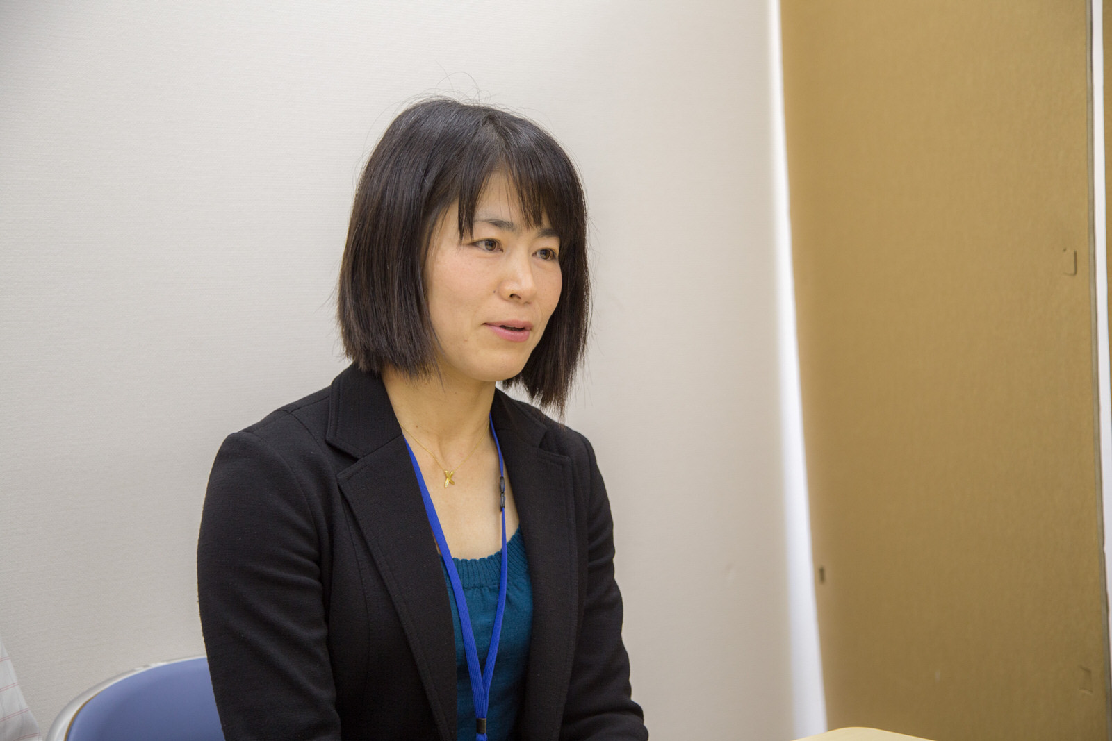 黒いジャケットを着た中村さんが椅子に座っている写真