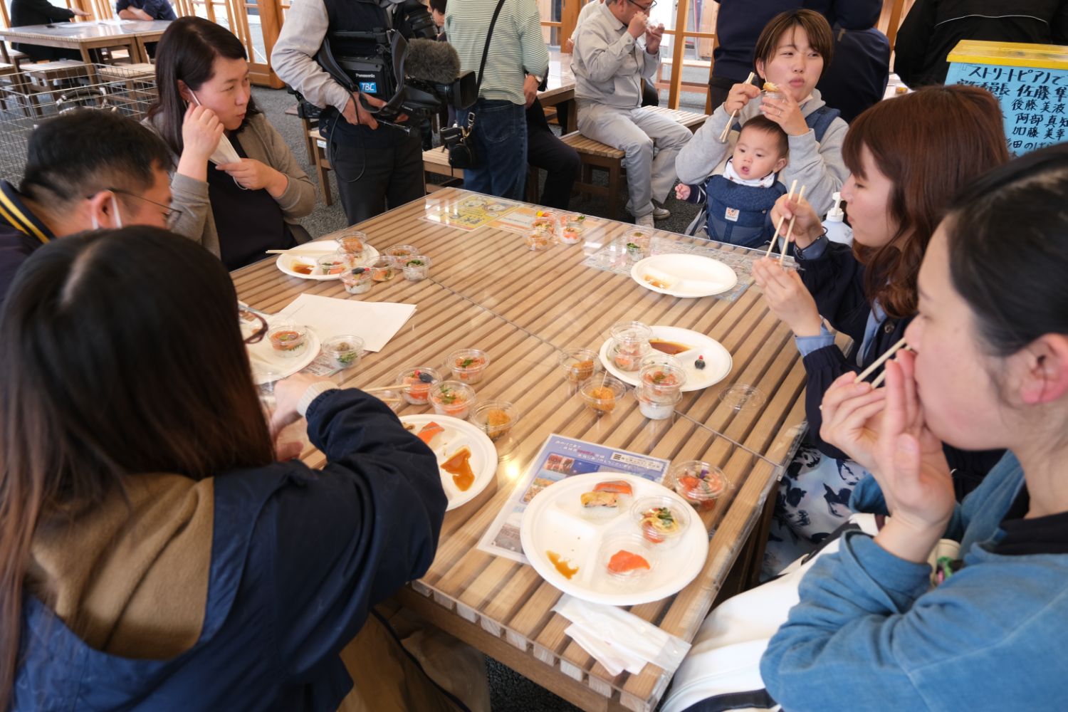 木製のテーブルを囲んで数人の人々が料理を食べている様子の写真