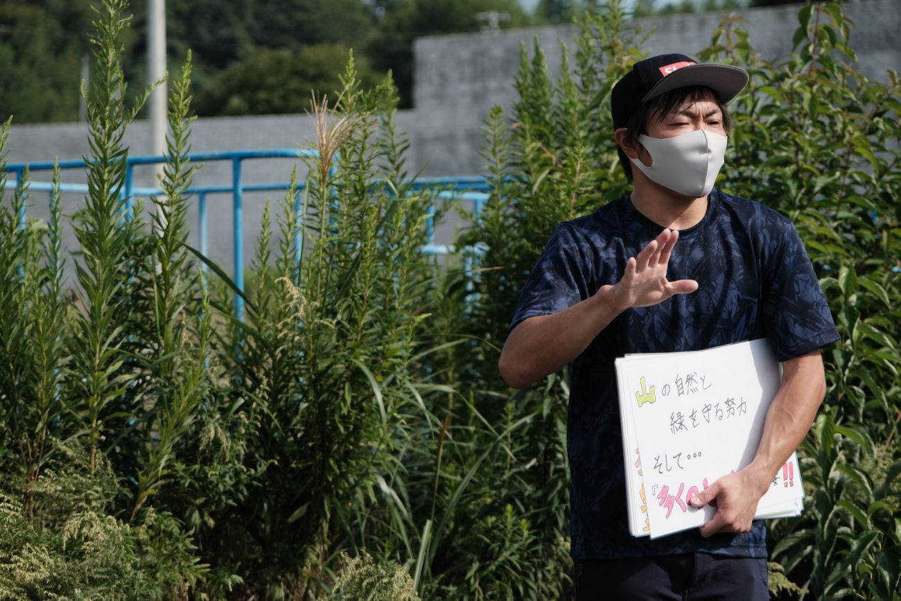 男性がマスクを着用し、自然や環境保護に関する説明をしている様子の写真