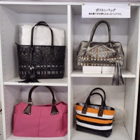 白い棚の中に黒やピンク、ストライプ柄などのボストンバッグが4つ並べられている写真