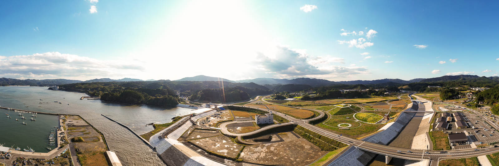 右手に濁った川の流れが海に注ぎ込み、左に整備中の港と山が続く、川と海の境界が分かりやすい湾東側の写真