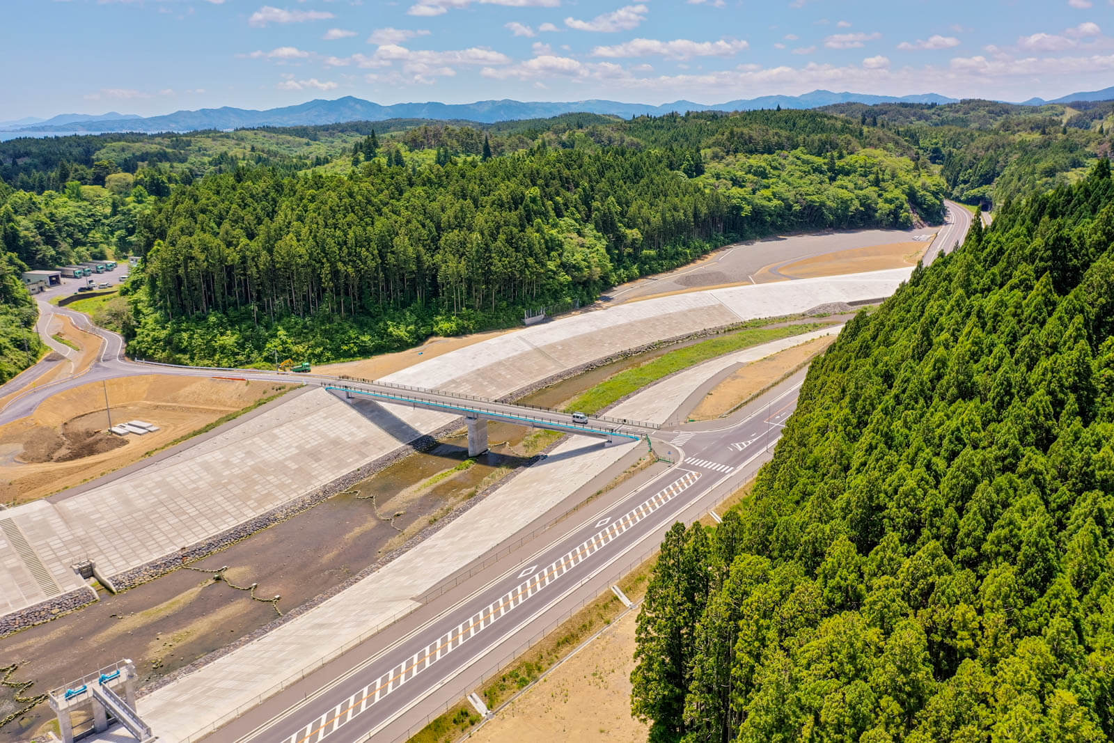 手前には二重構造の高い護岸壁と、それに沿う道路が見え、中央部には橋が架けられている様子を写した写真