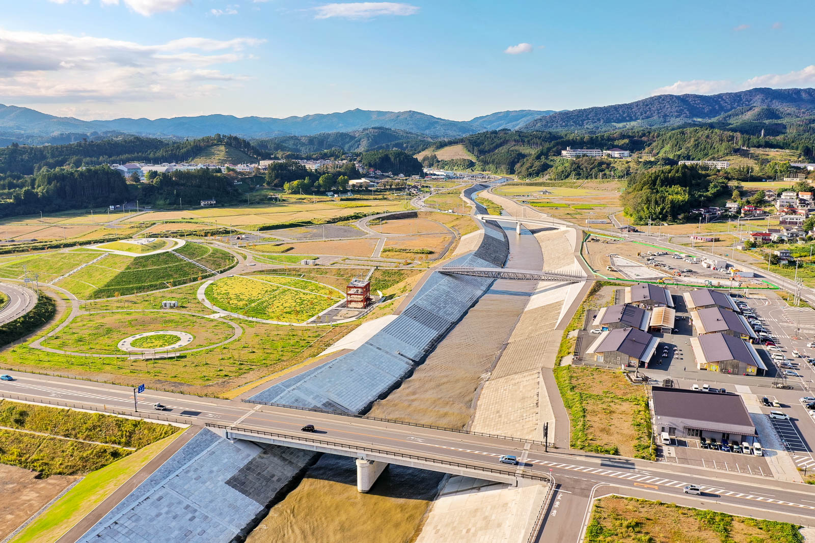 高台から見下ろした南三陸町の風景で、整備された広い堤防と公園、復興住宅や町並みが広がる様子が写っている写真