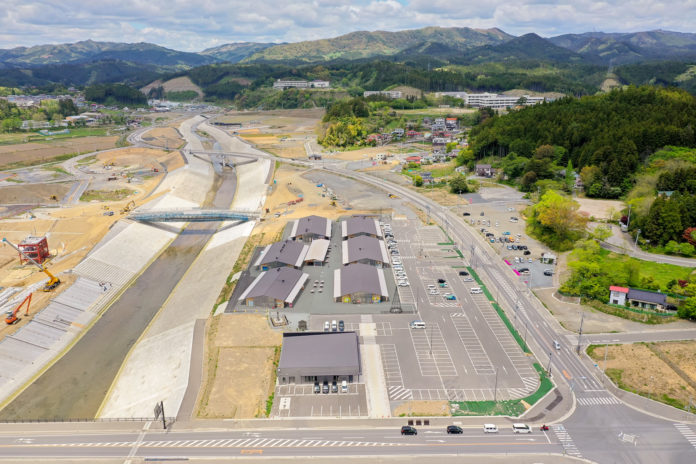 川沿いに複数の建物と広々とした駐車場が整備されており、周囲には緑が広がる穏やかな地域の様子を写した川沿いの施設の写真