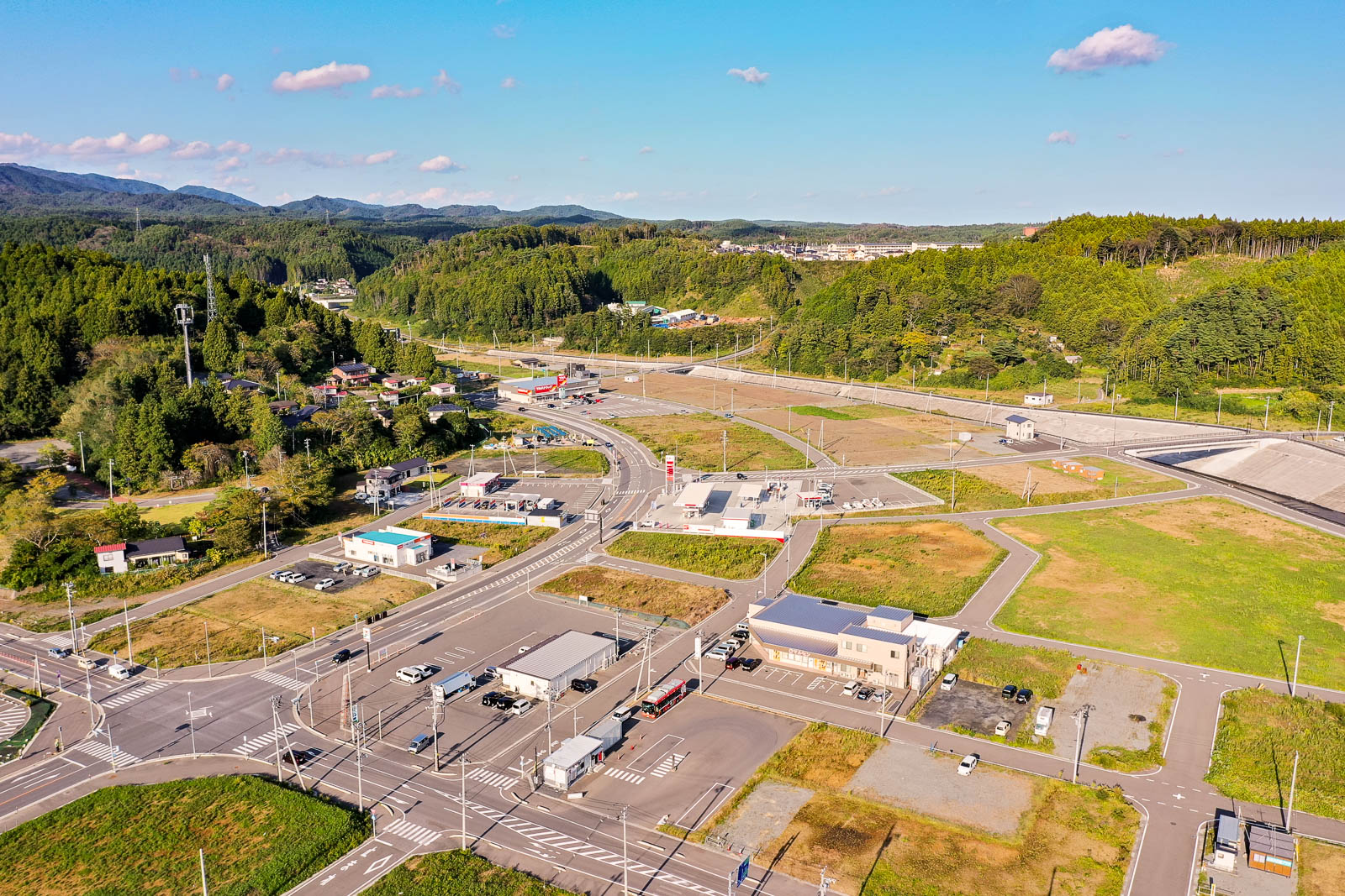 広大な土地にまっすぐ延びる人工河川と右手に整備された街区と道路網、遠方には山々が見渡せ、復興後に整備された地域の全貌を朝日に照らされた視点から見下ろした写真