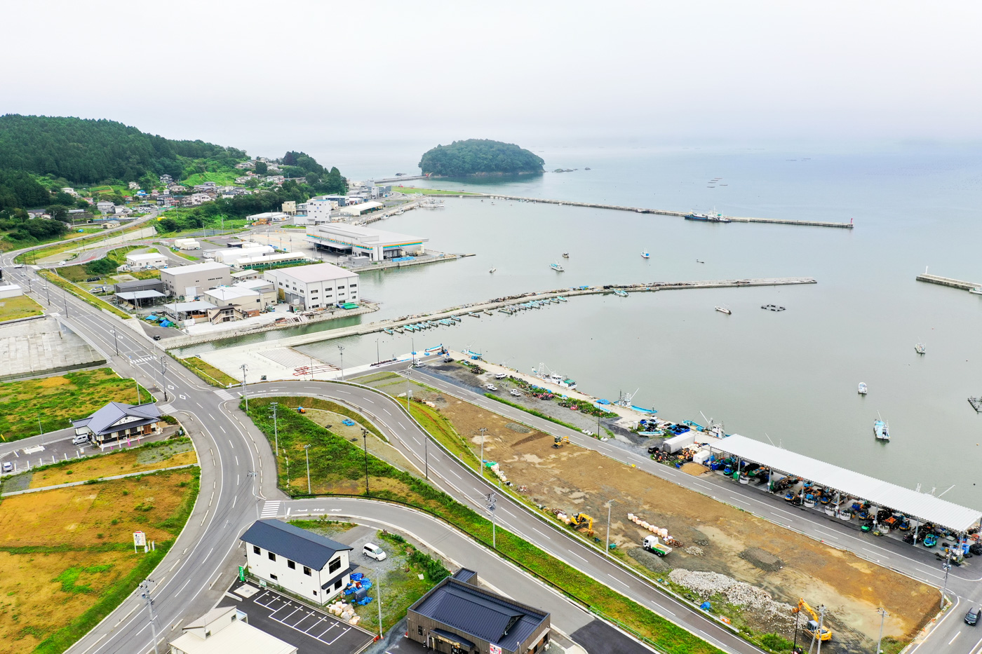 海に面した町の風景で、複数の道路が町中を走り、建物が密集して並び、海沿いには港が広がって船が停泊している様子が見える海沿いの町の写真