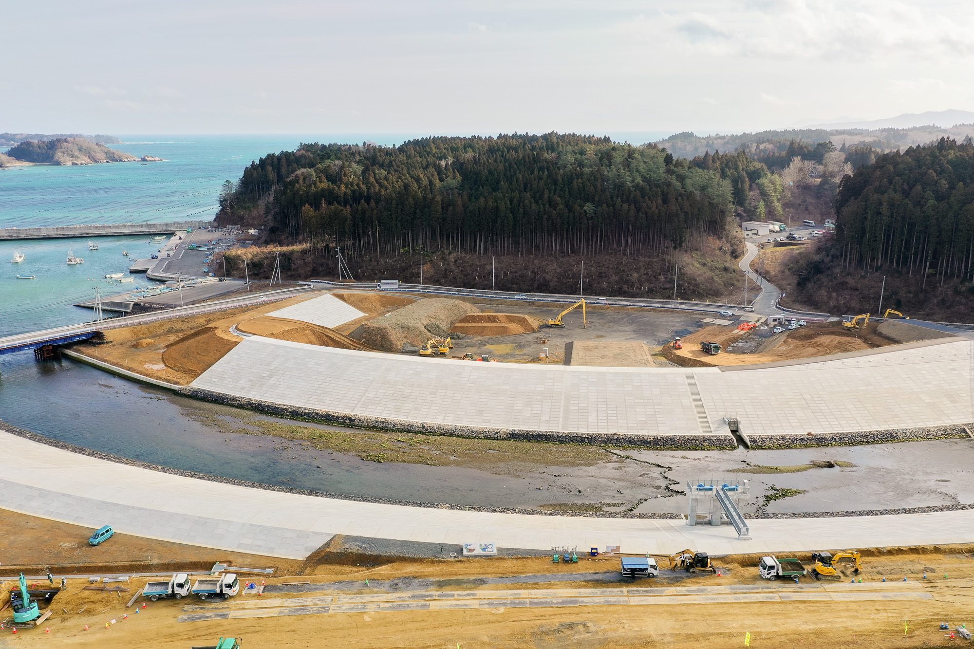 海岸沿いの工事現場を空から撮影した写真で、海に面した防波堤や護岸が建設されている様子が見える写真