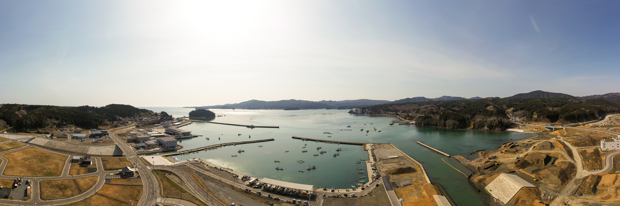 海に面した港町を高所から広く見渡し、建物や港の施設が密集し、海岸線に沿って町が広がっている様子を写した港町の写真
