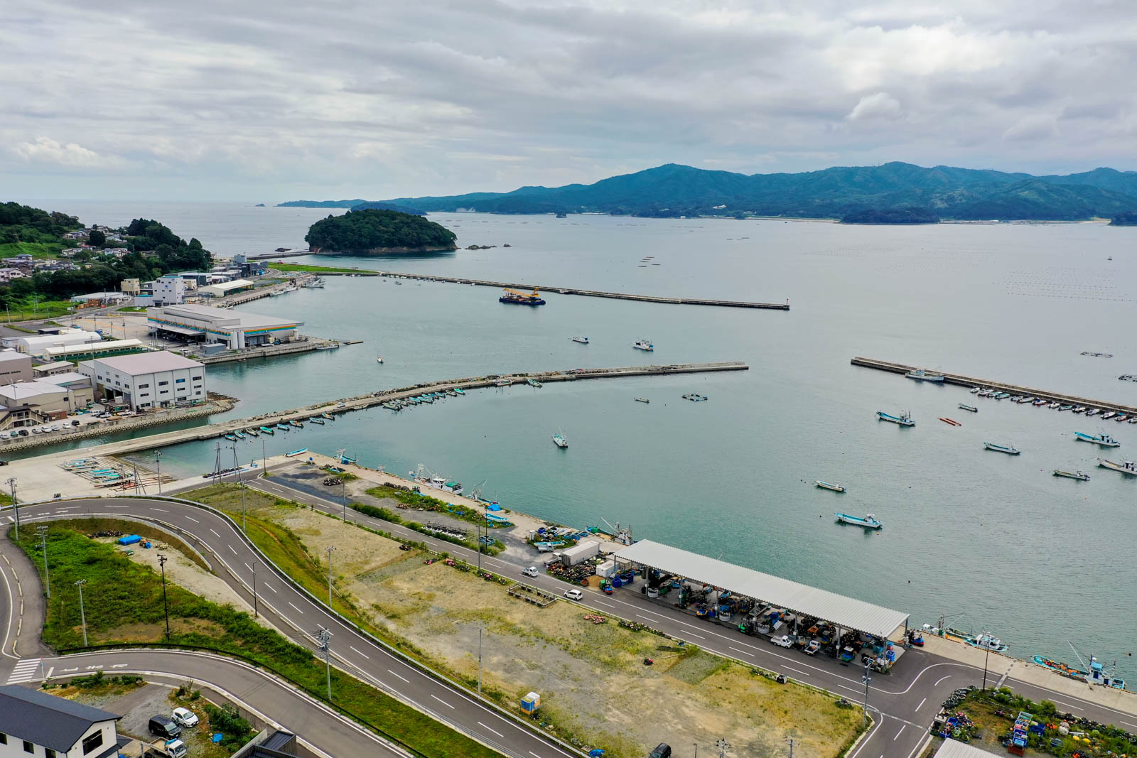 堤防沿いに立ち並ぶ商業施設や住宅、その奥にある住宅街と山、整備された道路網が確認できる写真