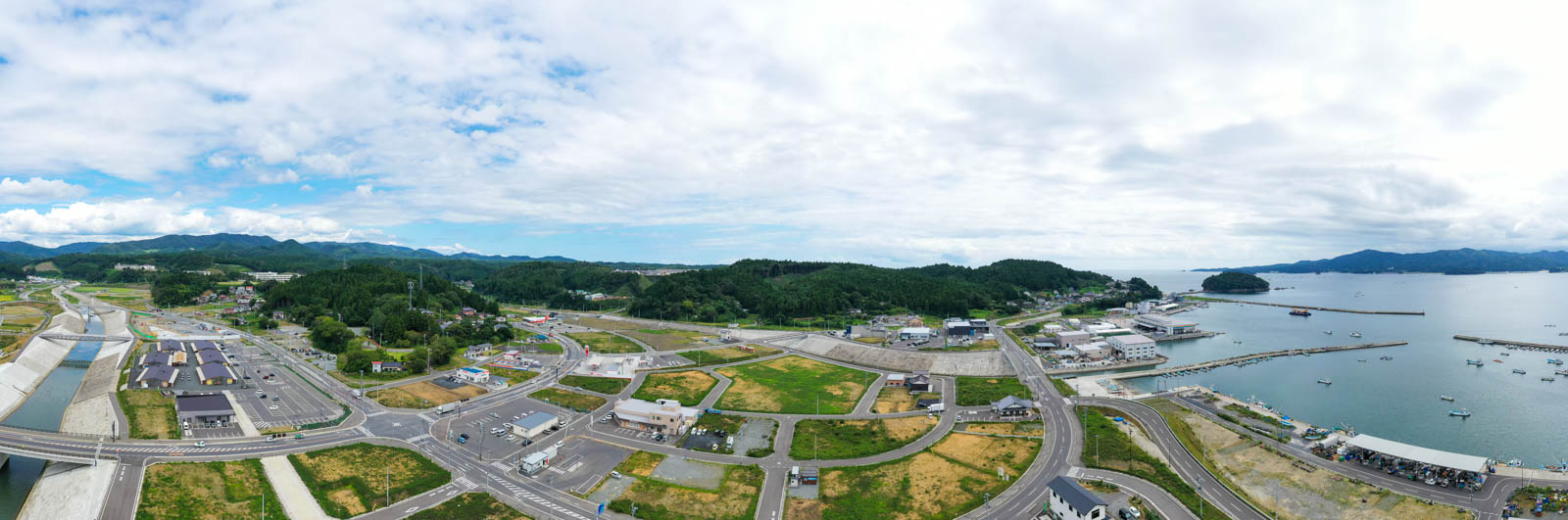 整備された川と道路を中心に、周囲に施設や商業施設が広がる沿岸地域のパノラマ写真