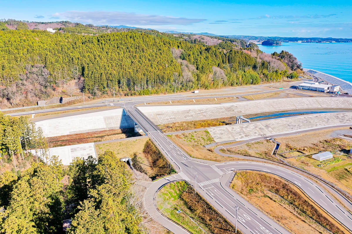 防潮堤や水門の整備が進められた海辺の交差点を上空から撮影した様子の写真