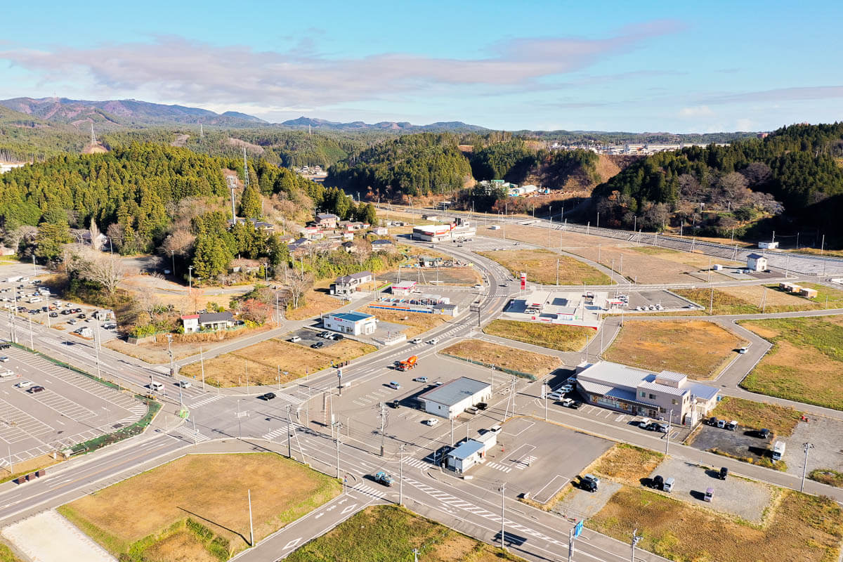 区画整理が行われていて、以前の密集した街並みとは異なり、車両の通行を優先した広い道路が配置されガソリンスタンドや店舗、事務所のような建物が見える写真