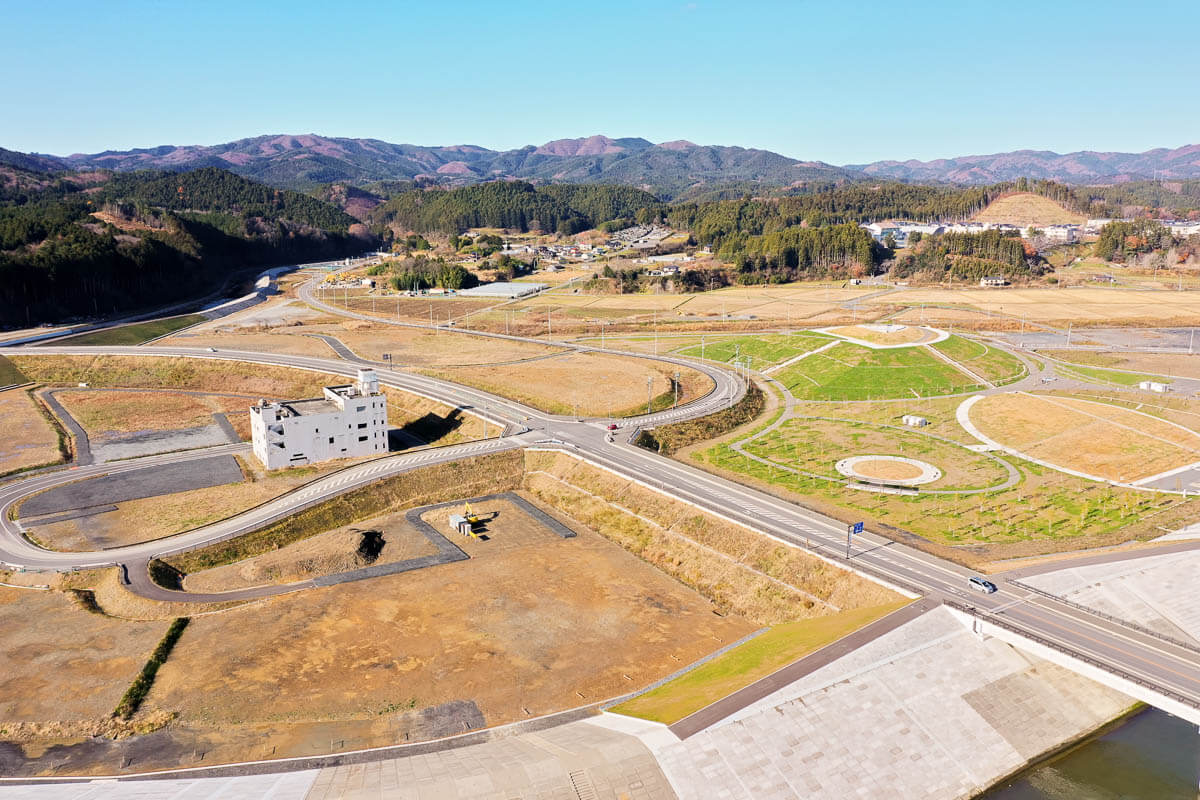 津波で被害を受けた鉄筋コンクリート建物が保存され円形の芝生エリアや散策路が整備されている写真