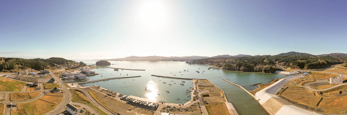 中央の海には、複数の防波堤が整備されており、船舶が安全に出入りできるようになって湾内には多くの漁船が停泊している様子を写した写真