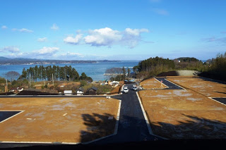 海を背景にした高台の造成地が広がっており、整地された土地の区画が並び、遠くに青い海と空が見える様子が写っている写真