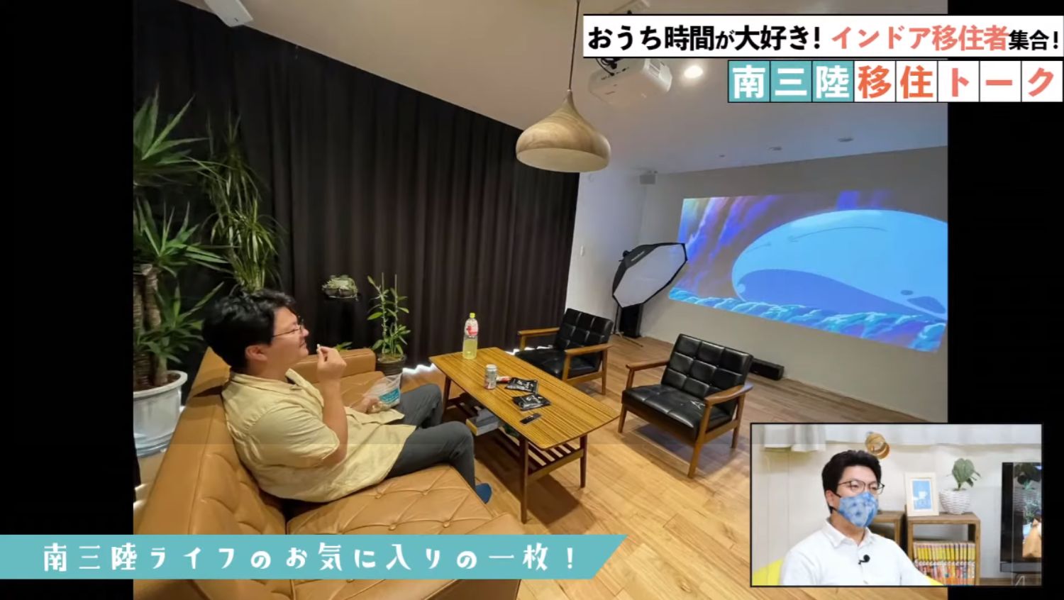ソファに座った男性がスナック菓子を手にしながら、壁にプロジェクターで映しているアニメ映像を部屋でくつろいで見ている様子で、右下に男性のワイプが小さく表示された画像