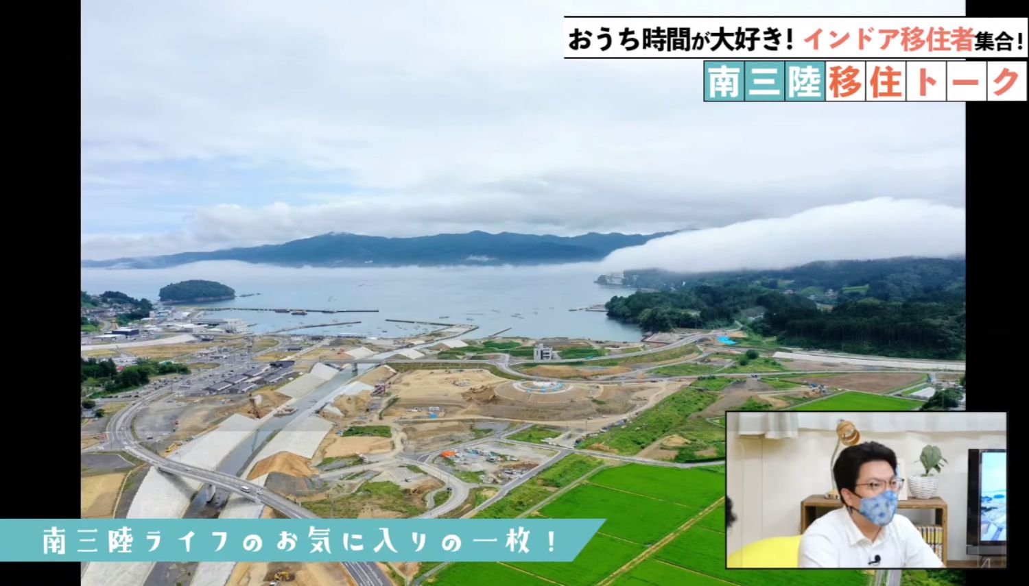 港町と海岸線、工事中の造成地が広がる空撮風景に、画面右下には出演者の男性のマスク姿がワイプで表示されている画像