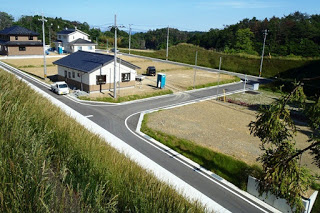 建物が数棟建ち始め、周囲に空き区画や工事用トイレが見える開発途中の宅地造成地の写真